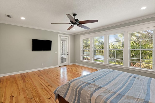 bedroom featuring a textured ceiling, light hardwood / wood-style floors, ceiling fan, and ornamental molding