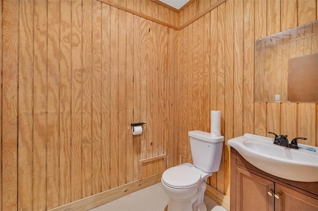 bathroom with vanity, wood walls, and toilet