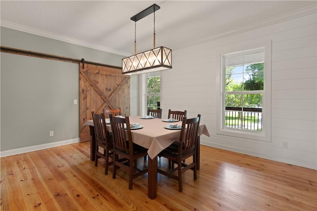 dining area featuring a barn door, a wealth of natural light, and light hardwood / wood-style floors