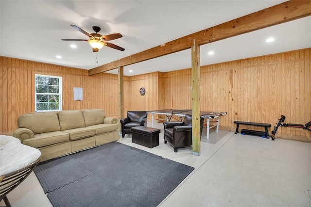 living room with wood walls, beamed ceiling, and ceiling fan