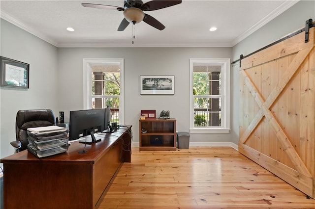 home office with a healthy amount of sunlight, a barn door, light wood-type flooring, and ornamental molding