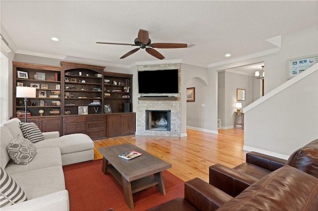 living room featuring a brick fireplace, ceiling fan, ornamental molding, and hardwood / wood-style flooring