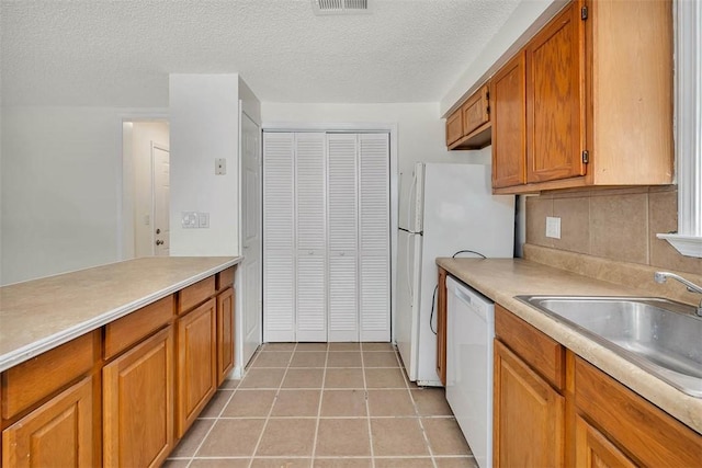 kitchen with light tile patterned floors, a textured ceiling, white dishwasher, and sink