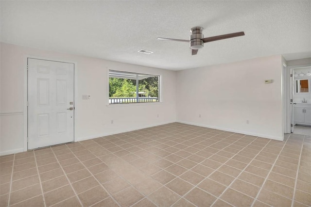 tiled spare room with ceiling fan and a textured ceiling