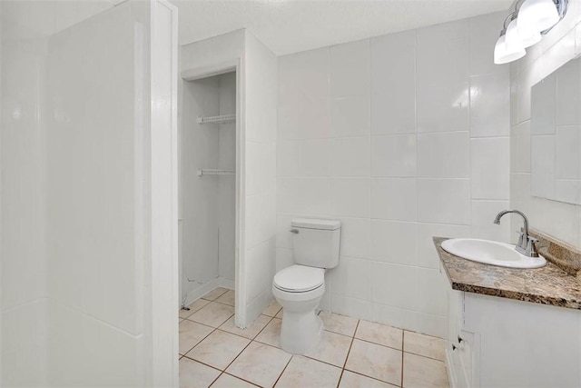 bathroom with tile patterned flooring, vanity, toilet, and tile walls