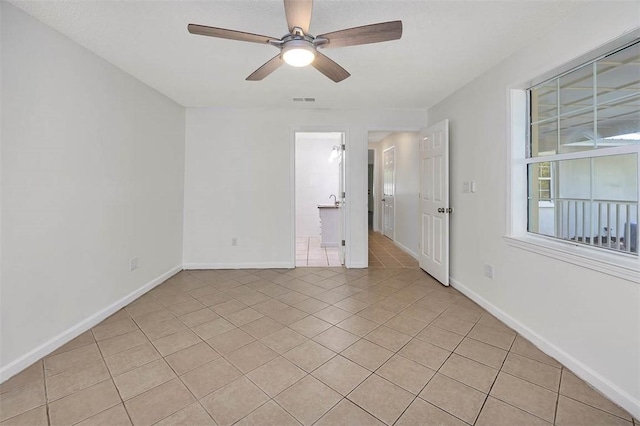 tiled spare room featuring ceiling fan