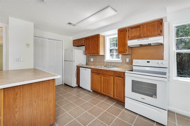 kitchen with a textured ceiling, sink, light tile patterned floors, and white appliances