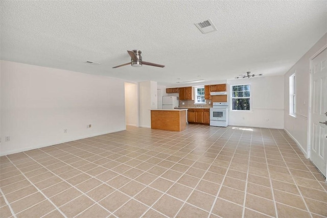 unfurnished living room featuring ceiling fan, light tile patterned floors, a textured ceiling, and track lighting