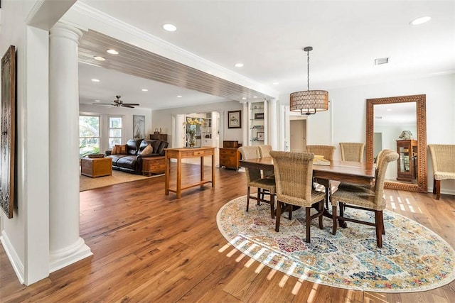 dining area featuring ceiling fan with notable chandelier, wood-type flooring, and ornate columns