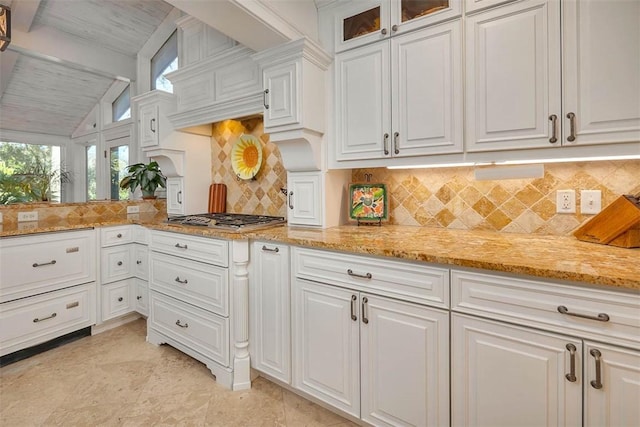 kitchen featuring tasteful backsplash, white cabinetry, stainless steel gas stovetop, and lofted ceiling