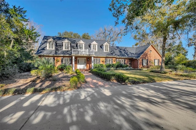 cape cod house featuring a front yard