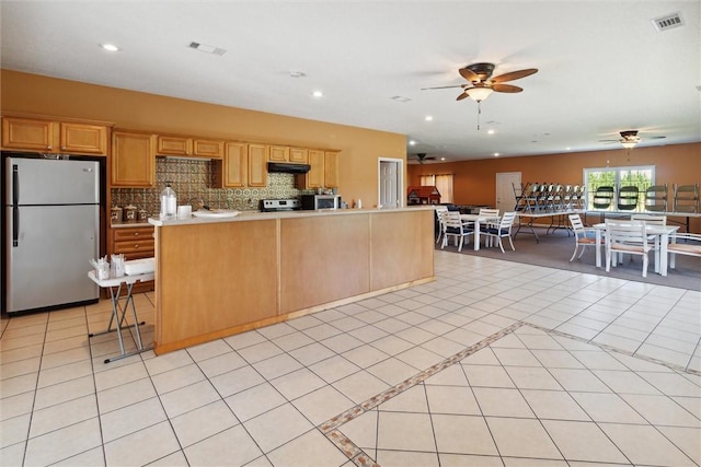 kitchen featuring stainless steel refrigerator, ceiling fan, backsplash, light tile patterned floors, and range