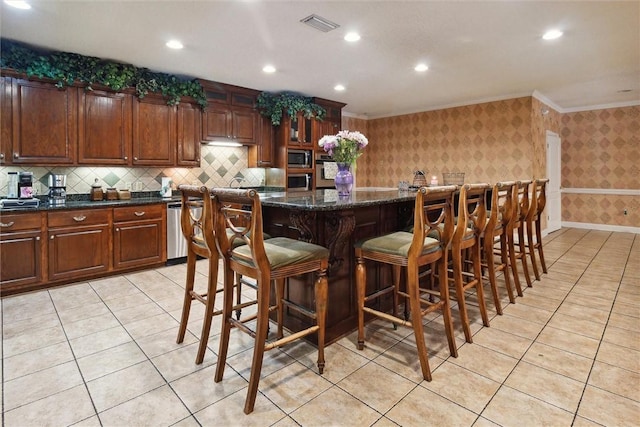 kitchen featuring dark stone countertops, a center island, stainless steel appliances, and ornamental molding