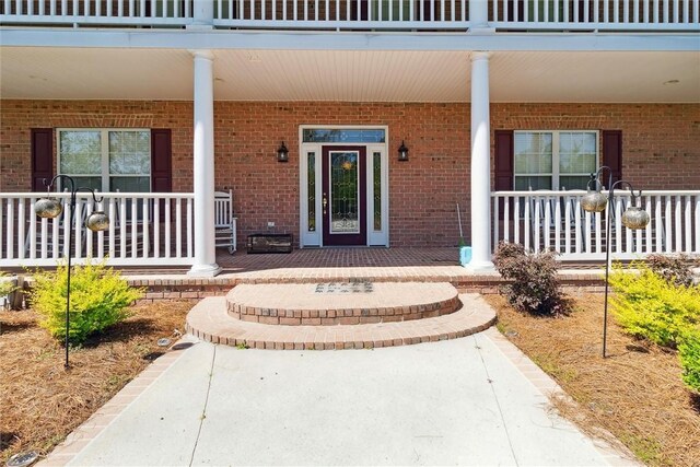 entrance to property featuring a porch and a balcony