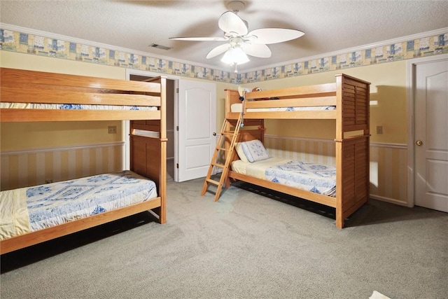 bedroom featuring ceiling fan, crown molding, carpet, and a textured ceiling