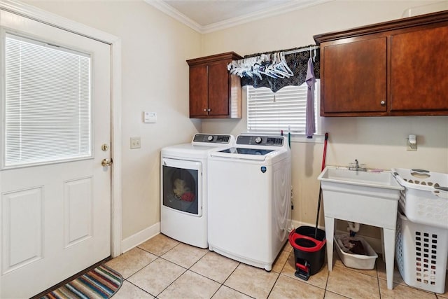 clothes washing area with washing machine and clothes dryer, crown molding, light tile patterned floors, and cabinets