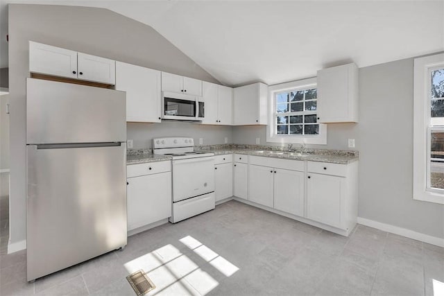 kitchen featuring white appliances, light stone countertops, vaulted ceiling, white cabinetry, and sink