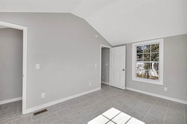 tiled spare room with vaulted ceiling