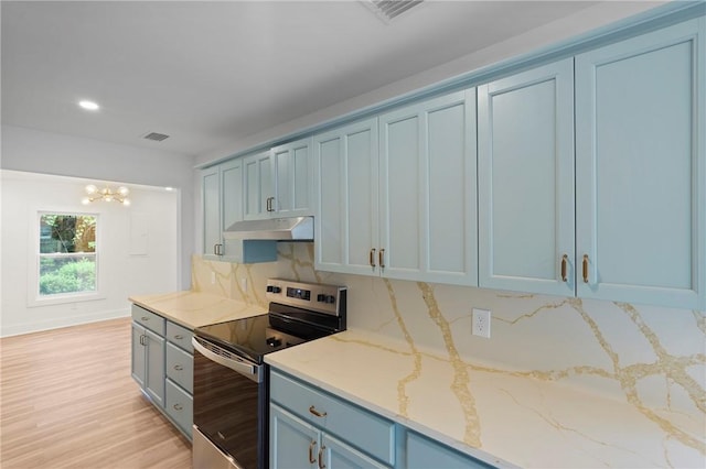98 Atlantic Dr, Saint Simons Island, GA 31522 - kitchen with stainless steel electric range oven, under cabinet range hood, blue cabinets, light stone counters, and a chandelier