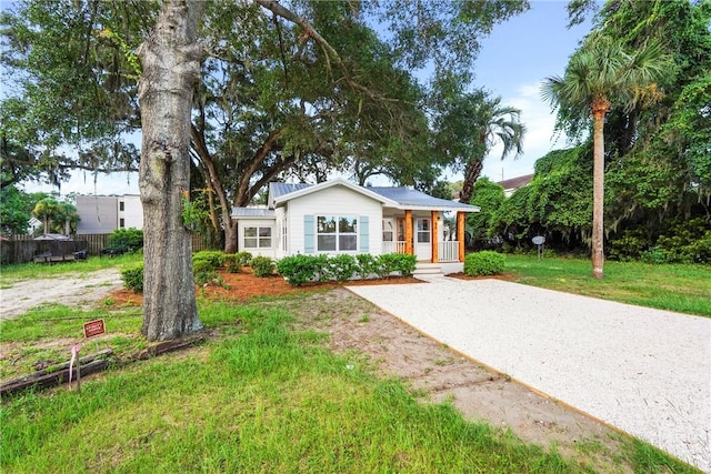 98 Atlantic Dr, Saint Simons Island, GA 31522 - view of front of home featuring a front yard, a metal roof, gravel driveway, and a porch