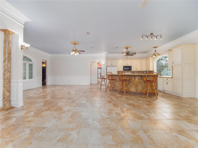 living room with ceiling fan, ornamental molding, and decorative columns