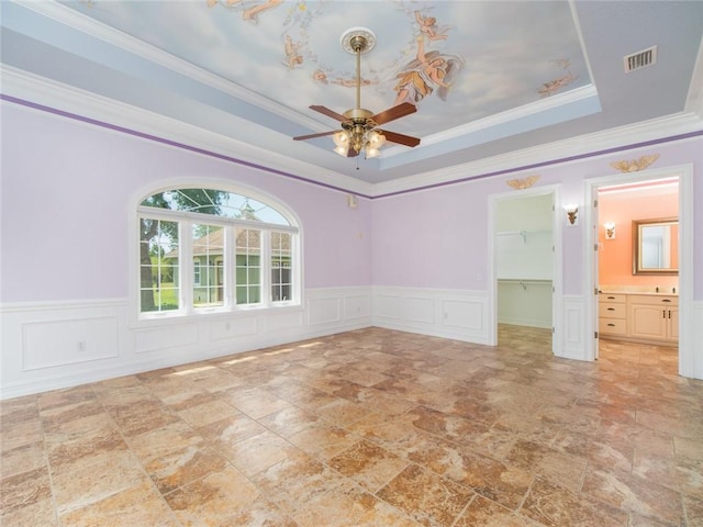 unfurnished room with a tray ceiling, ceiling fan, and crown molding