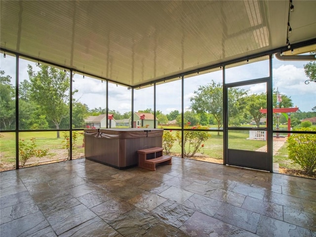 unfurnished sunroom featuring plenty of natural light and a hot tub