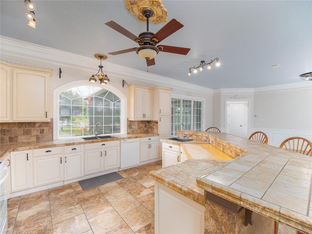 kitchen with dishwasher, a breakfast bar, sink, crown molding, and hanging light fixtures