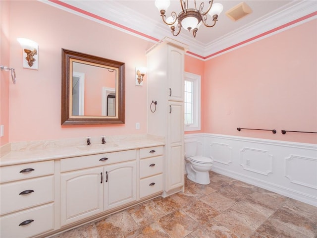 bathroom with a notable chandelier, toilet, ornamental molding, and vanity