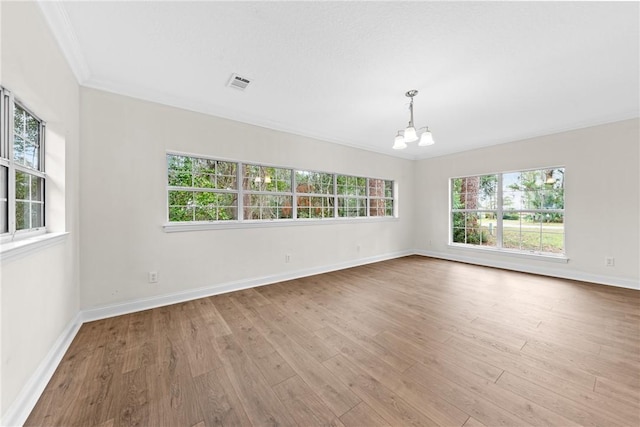 spare room featuring a chandelier, light hardwood / wood-style flooring, and ornamental molding