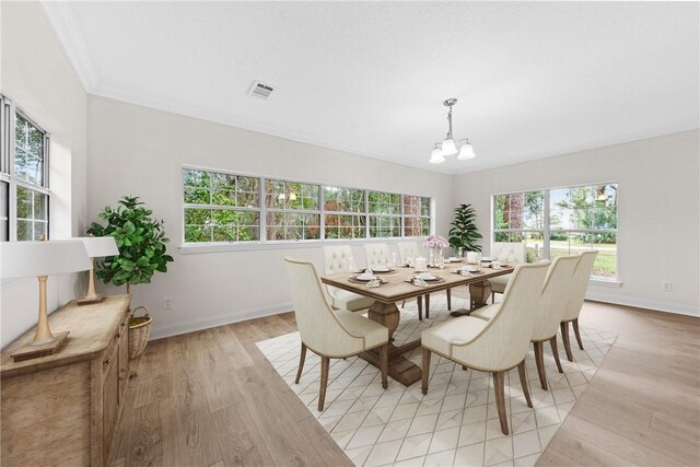 dining space with a chandelier, light hardwood / wood-style floors, and ornamental molding