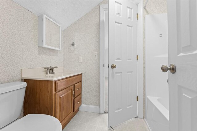 bathroom with a textured ceiling, vanity, toilet, and lofted ceiling