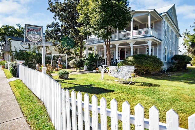 view of front of house featuring a balcony and a front yard