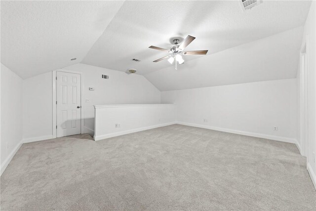 bonus room with a textured ceiling, light colored carpet, and vaulted ceiling