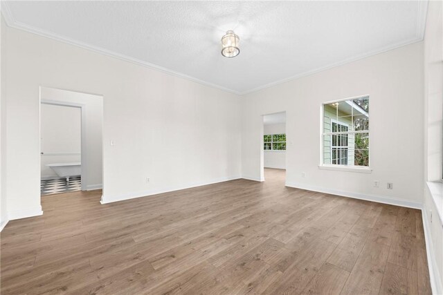 empty room featuring hardwood / wood-style floors, ornamental molding, and a textured ceiling