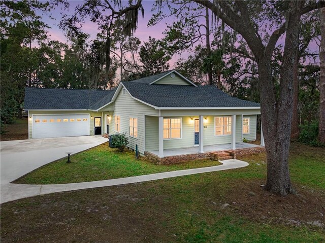 ranch-style home featuring a porch, a yard, and a garage