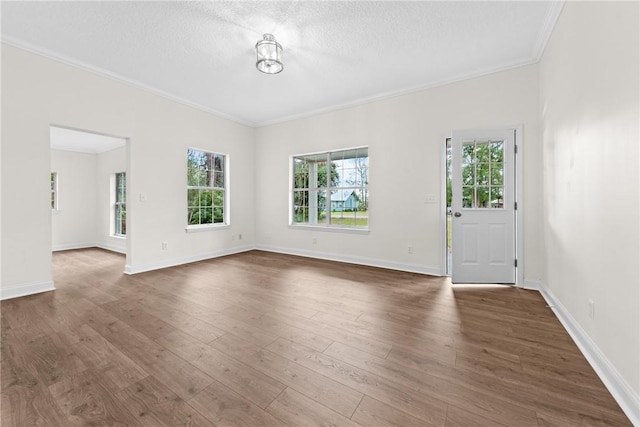 unfurnished living room with a textured ceiling, ornamental molding, and dark wood-type flooring