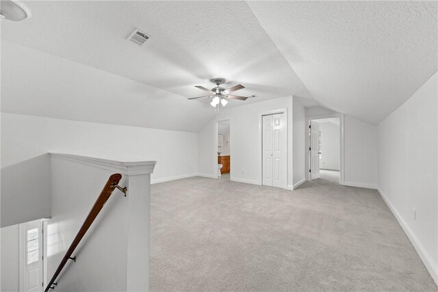 bonus room with a textured ceiling, light carpet, and vaulted ceiling