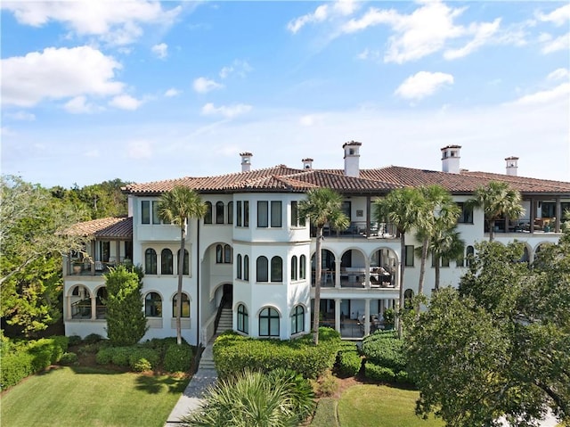 back of house featuring a balcony and a lawn