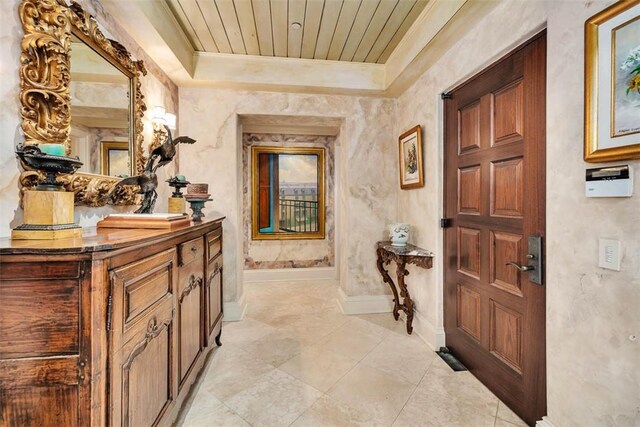 hallway featuring light tile patterned floors, a raised ceiling, and ornamental molding