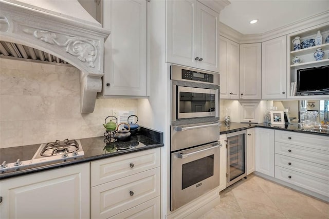 kitchen featuring white cabinetry, wine cooler, white gas stovetop, premium range hood, and dark stone countertops