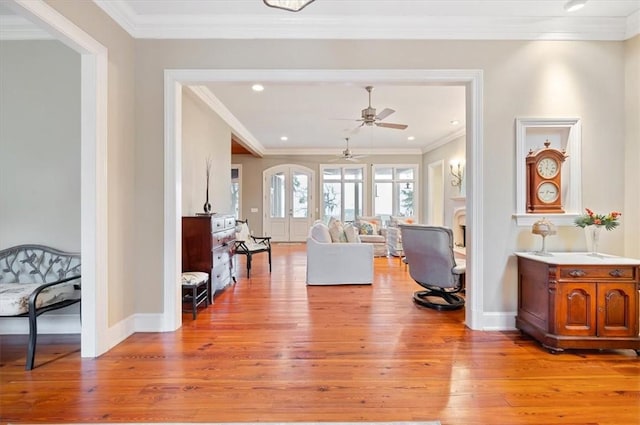 living room with ceiling fan, light wood-type flooring, crown molding, and baseboards