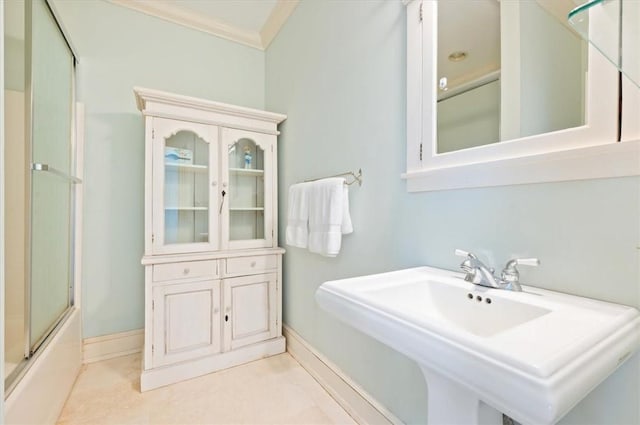 full bathroom featuring baseboards, shower / bath combination with glass door, a sink, crown molding, and tile patterned floors