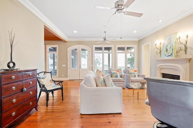 living area with light wood finished floors, a fireplace, crown molding, and baseboards