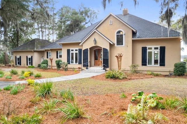 view of front of home with stucco siding and a chimney