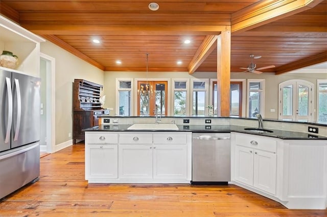 kitchen featuring dark countertops, ornamental molding, appliances with stainless steel finishes, white cabinetry, and a sink