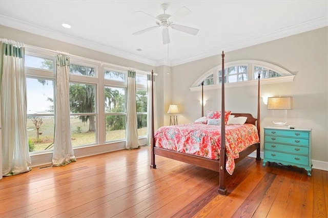 bedroom featuring ornamental molding, a ceiling fan, baseboards, and hardwood / wood-style flooring