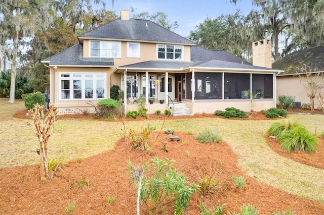 back of house featuring a lawn, a chimney, and a sunroom