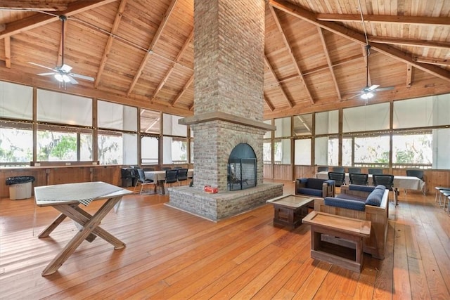 living area featuring wood ceiling, beamed ceiling, a brick fireplace, and hardwood / wood-style floors