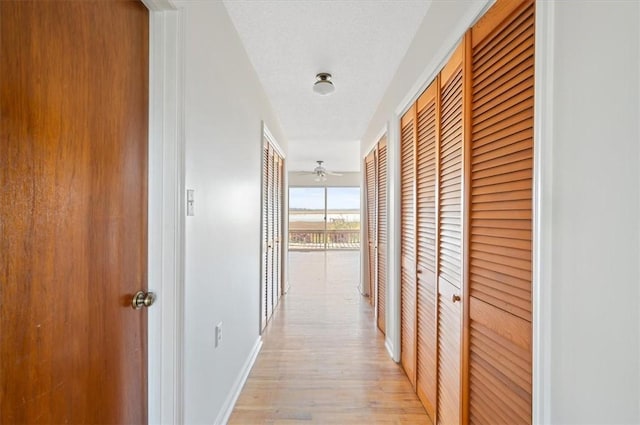 corridor with light wood finished floors and baseboards